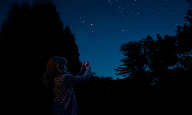 a child holding the light meter up to a dark starry sky.